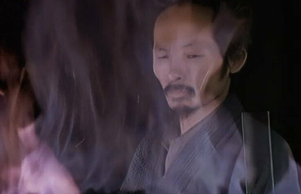 un maître forgeron japonais derrière les flammes de la forge façonne la lame d'un katana